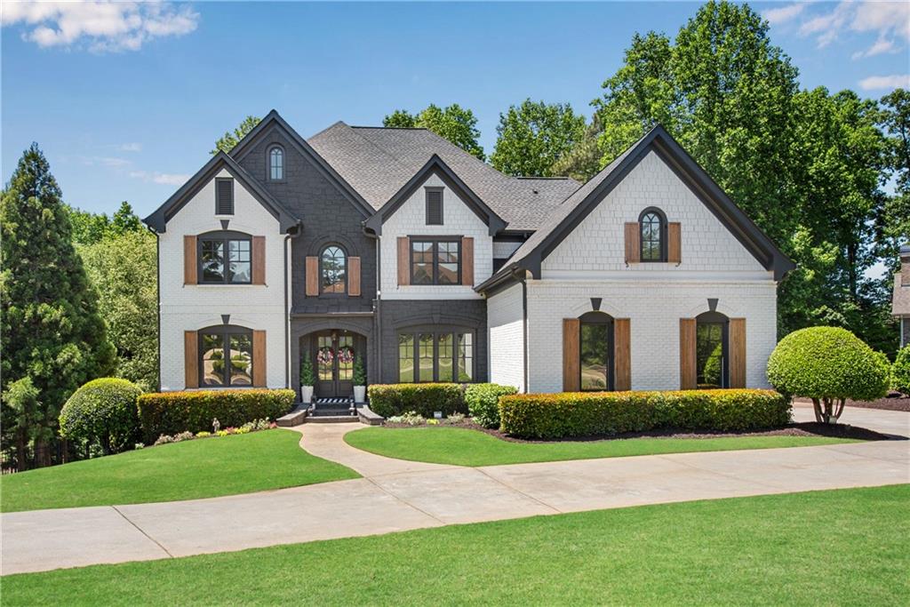 Front elevation of 3075 Wills Mill Road: a two-story white-brick estate with dark shutters and arched windows, manicured front lawn with rounded boxwood hedges and a curved entry walkway