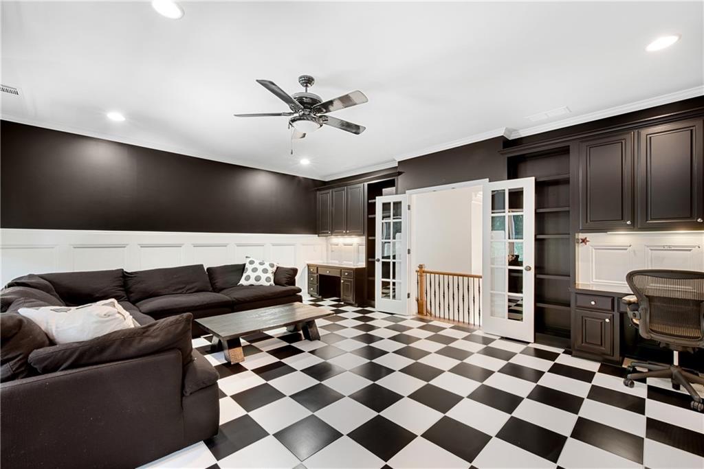 Gourmet kitchen at 3075 Wills Mill: a large island with white marble top and dark cabinetry, brass wagon-wheel chandelier overhead, white cabinetry, integrated paneled refrigerator, breakfast room visible through arched openings